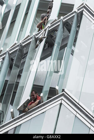Arbeiter, die Montage externer Glas Lamellen an Energie effiziente neue Bürogebäude in Spanien Stockfoto