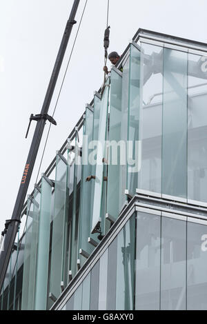 Arbeiter, die Montage externer Glas Lamellen an Energie effiziente neue Bürogebäude in Spanien Stockfoto