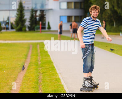 Urlaub, aktiven Lebensstil Freiheit Konzept. Junge fit Mann auf Roller-Skates Reiten im Freien auf Straße, Kerl Rollerbladen an sonnigen Tag Stockfoto