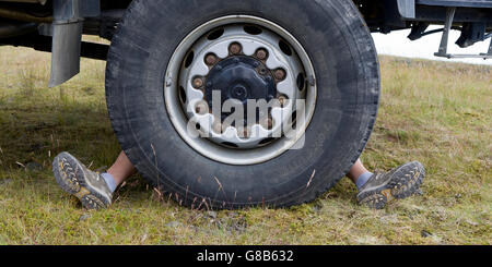 Mann hinter einem großen Reifen von einem großen Bus, Island Stockfoto