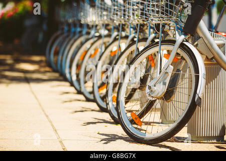 Reihe von geparkten Oldtimer Fahrräder Fahrräder zu vermieten auf Bürgersteig. Nahaufnahme von Rad und Fahrrad Scheinwerfer Stockfoto