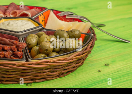 Korb mit spanischen Tapas auf einem rustikalen Holztisch grün Stockfoto