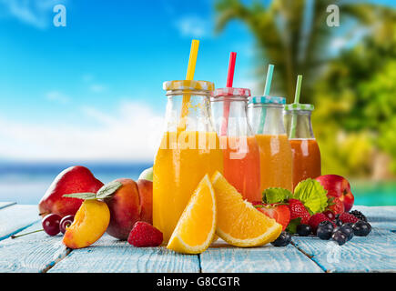 Frische Gläser Saft mit Obst mischen platziert am Strand auf Holzbohlen. Konzept der gesunde Getränke, Antioxidantien und Sommer c Stockfoto