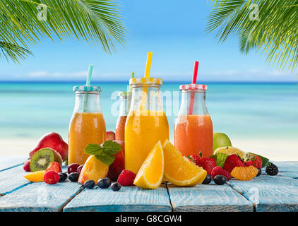 Frische Gläser Saft mit Obst mischen platziert am Strand auf Holzbohlen. Konzept der gesunde Getränke, Antioxidantien und Sommer c Stockfoto