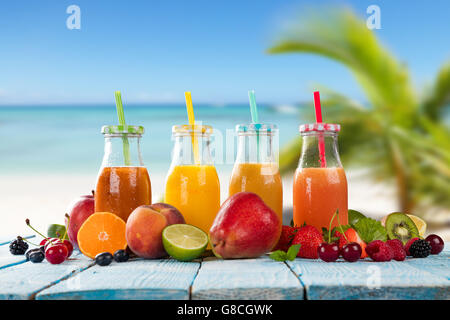 Frische Gläser Saft mit Obst mischen platziert am Strand auf Holzbohlen. Konzept der gesunde Getränke, Antioxidantien und Sommer c Stockfoto