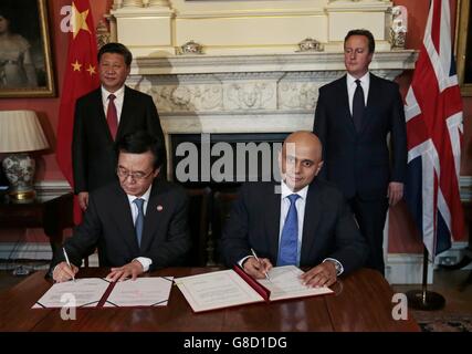 Wirtschaftsminister Sajid Javid und Chinas Minister Gao Hucheng unterzeichnen am zweiten Tag seines Staatsbesuchs in Großbritannien eine Vereinbarung, während Premierminister David Cameron und Chinas Präsident Xi Jinping in der Downing Street 10 in London zuschauen. Stockfoto