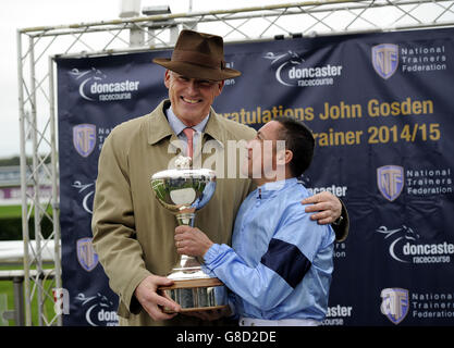 Trainer John Gosden erhält die Trainer Flat Championship Trophy vom Jockey Frankie Dettori am zweiten Tag des Racing Post Trophy-Wochenendes auf der Doncaster Racecourse. Stockfoto