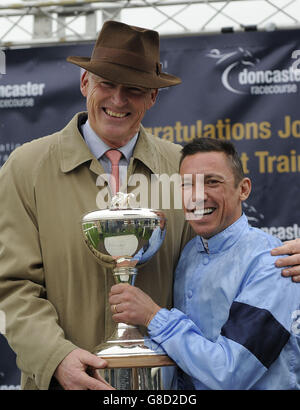 Trainer John Gosden erhält die Trainer Flat Championship Trophy vom Jockey Frankie Dettori am zweiten Tag des Racing Post Trophy-Wochenendes auf der Doncaster Racecourse. Stockfoto