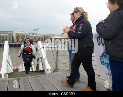 Die britische Abenteurerin Sarah Ouen (links) läuft die Gangway hinauf, um Bruder Matt Ouen (dritte rechts), Verlobte Lucy Allen (zweite rechts) und Mutter Helen Ouen (rechts) zu begrüßen, nachdem sie unter der Tower Bridge mit dem Kajak gefahren ist, um ihr viereinhalb Jahre lang London2London zu absolvieren: Über die Weltexpedition, die sie 25,000 Meilen um die Welt radeln, Kajak fahren und rudern sah. Stockfoto