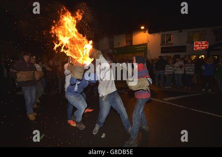 Erwachsene aus dem Dorf Ottery St Mary in Devonshire tragen das traditionelle Tar Barrel in der Bonfire Night durch die Straßen des Dorfes. Stockfoto