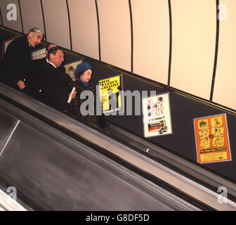 Die Queen schaut sich Plakate an, auf denen der Steve McQueen-Film „Bullitt“ steht, während sie die Rolltreppe der U-Bahn-Station Green Park entlang fährt, während sie den neuen Abschnitt der Victoria-Linie der Londoner U-Bahn eröffnet. Stockfoto