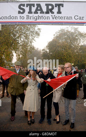 Alex Jones (zweiter links) Ken Bruce (Mitte) und Chris Evans (rechts) zerreißen die rote Flagge an der Startlinie während des Bonhams London to Brighton Veteran Car Run, London. Stockfoto