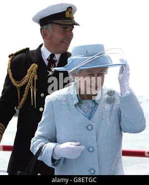 Die britische Königin Elizabeth II. Hält ihren Hut, als sie mit Admiral Sir Alan West in Portsmouth an der HMS Endurance auf ihrem Weg zur Überprüfung der Flotte ansteht. Insgesamt 167 Schiffe der Royal Navy und 35 Nationen nehmen an der International Fleet Review in Spithead, vor Portsmouth, Teil, als Teil der Trafalgar 200 Feierlichkeiten in dieser Woche. Stockfoto