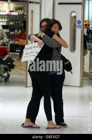 Die britische Filmemacherin Becky Prosser (nächste Kamera), die wegen Verstoßes gegen die Einwanderungsgesetze in Indonesien inhaftiert war, umarmt ihre Schwester Natalie, als sie am Flughafen Heathrow ankommt. Stockfoto