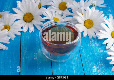 Kamillentee in einer Tasse auf einem blauen Holztisch Stockfoto