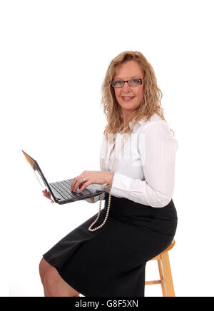 Eine Business-Frau sitzt in einem schwarzen Rock weißen Bluse halten ihren Laptop und arbeiten daran, für weißen Hintergrund isoliert. Stockfoto