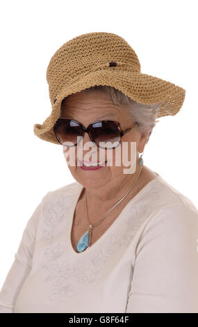 Eine schöne ältere Frau in den Siebzigern trägt einen Strohhut und Sonnenbrille, Lächeln, isoliert für weißen Hintergrund. Stockfoto