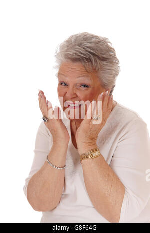 Eine grauen Haaren Senioren Frau mit ihren Händen auf ihr Gesicht, Lächeln und freut sich sehr, für weißen Hintergrund isoliert. Stockfoto