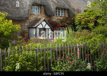 Ein traditionelles Stein Reetdachhaus mit lattenzaun und ein Garten voller bunter typische Cottage Garten Blumen, Exton, Rutland, England Stockfoto