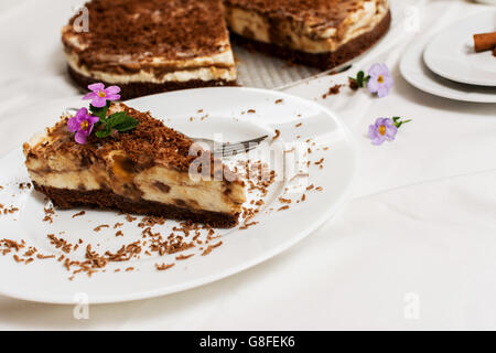 Traditionellen Karamell Käsekuchen mit Schokolade und Blumen auf weißem Teller Stockfoto