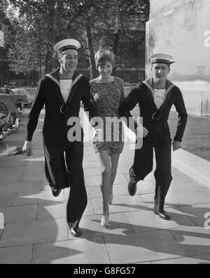 Cilla Black, der Radio- und Fernsehstar, kommt mit ihren Eskorten, R.E.M., an Trevor Henshaw (l), 24, aus Brighton, Sussex und E.M. Eric Heath, 19, aus Gloucester, als sie zum Verteidigungsministerium (Navy Department) in London ging, um eine persönliche Weihnachtsbotschaft auf einem Masterband aufzuzeichnen. Stockfoto