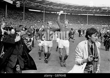 Der englische Jack Charlton (r) hält die Jules Rimet-Trophäe hoch, während er sie mit den Teamkollegen Ray Wilson (l), George Cohen (2. L) und Bobby Moore (2. R) nach ihrem Sieg von 4-2 um Wembley pariert Stockfoto