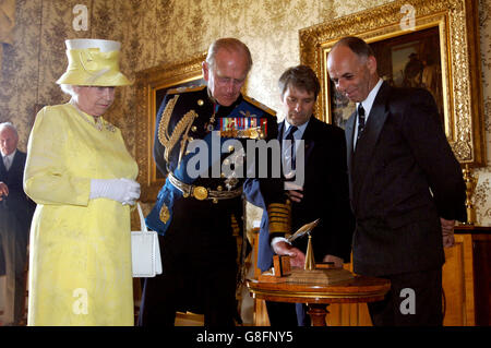 Queen Elizabeth II. Und der Herzog von Edinburgh werden von Chris Bennett (zweiter rechts) und Steve Vizard mit einer Skulptur des Orgelkämpfers präsentiert, die aus der Rettung eines echten Orwanzes im Buckingham Palace gefertigt wurde. Das Modell wurde aus dem Triebwerksblock eines von Buckingham Palace in der Schlacht von Großbritannien gefertigten, der den Buckingham Palace vor einem direkten Treffer rettete. Stockfoto