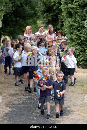 Die Kinder der Wilden All Saints School führen eine jahrhundertealte Tradition fort, während sie am Grab eines 1899 verstorbenen cowmans Blumen legen. Thomas Jones überließ seinen gesamten Besitz den Kindern des Dorfes unter der Bedingung, dass sie jedes Jahr an seinem Geburtstag, dem St.-Smhen-Tag, im Dorf Wilden in Worcestershire, ein Lied sangen und Blumen über sein Grab legten. Stockfoto