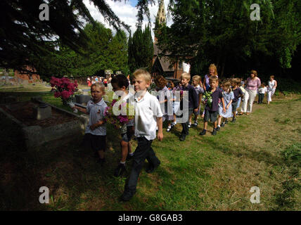 Kinder der Wilden All Saints School setzen eine jahrhundertealte Tradition fort, als sie Blumen am Grab eines cowman legten, der 1899 starb. Thomas Jones überließ seinen gesamten Besitz den Kindern des Dorfes unter der Bedingung, dass sie jedes Jahr an seinem Geburtstag, dem St.-Swithen-Tag, ein Lied sangen und Blumen über sein Grab im Worcestershire-Dorf Wilden legten. Stockfoto