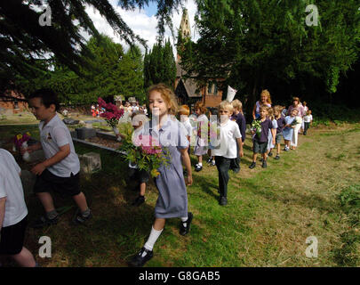 Kinder der Wilden All Saints School setzen eine jahrhundertealte Tradition fort, als sie Blumen am Grab eines cowman legten, der 1899 starb. Thomas Jones überließ seinen gesamten Besitz den Kindern des Dorfes unter der Bedingung, dass sie jedes Jahr an seinem Geburtstag, dem St.-Swithen-Tag, ein Lied sangen und Blumen über sein Grab im Worcestershire-Dorf Wilden legten. Stockfoto