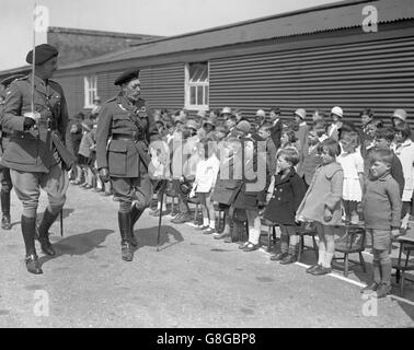 König Georg V., der an einigen Kindern von Männern des Panzerkorps in den Kasernen, Lulworth, vorbeikam. Genaues Datum unbekannt. Stockfoto