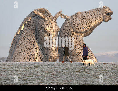 Hundewanderer passieren die Kelpies in der frühen Morgensonne auf dem Forth und Clyde Kanal in der Nähe von Falkirk, nach starkem Frost über Nacht durch Zentralschottland. Stockfoto