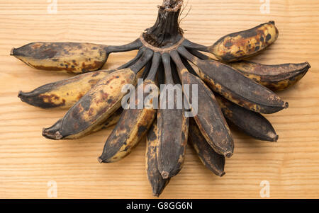 Bündel von schwarzen überreife Bananen auf einem hölzernen Hintergrund Stockfoto