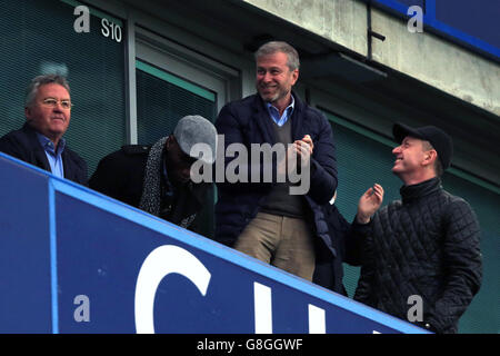 Chelsea-Interimsmanager Guus Hiddink (links) schaut von der Tribüne neben dem ehemaligen Chelsea-Spieler Didier Drogba (Mitte), wie Chelsea-Besitzer Roman Abramovich (rechts) während des Barclays Premier League-Spiels in Stamford Bridge, London, als Chelsea-Score feiert. Stockfoto