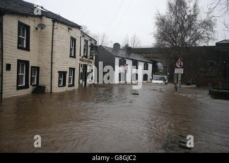 Ein Fahrzeug fährt durch Überschwemmungswasser bei Mytholmroyd in Calderdale, West Yorkshire, wo nach sintflutartigen Regengüssen Hochwassersirenen erklingen. Stockfoto