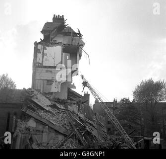 Es bestand die große Gefahr, dass das hoch aufragende Mittelstück dieses unter Abriss stehenden Gebäudes in die falsche Richtung in die Shirland Road, Maida Vale, So kletterten zwei wagemutige Abbrucharbeiter Harry Shailey und Cyril Bere den Jib des Krans hinauf und befestigten einen Falschmann, damit er wie geplant heruntergefahren werden konnte. Der Grund für die plötzliche Gefahr war, dass im alten Gebäude, der ehemaligen Transkriptionsabteilung der British Broadcasting Corporation, während früherer Abrissarbeiten ein Feuer ausbrach und der Turm sich über den falschen Weg lehnte. Auf diesem Bild sind die Männer zu sehen Stockfoto