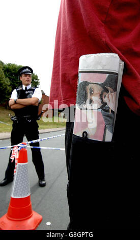 Ein Bewohner des Hyde Park-Bereichs von Leeds mit einer Zeitung, die das Foto des Selbstmordattentäters Mohammed Khan trägt, wartet auf eine Polizeikorde, während Armeeangriffe und Polizei den Bereich überprüfen, nachdem sie weitere Straßen abgedichtet haben. Stockfoto