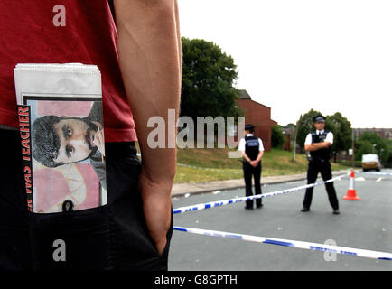 Ein Bewohner des Hyde Park-Bereichs von Leeds mit einer Zeitung, die das Foto des Selbstmordattentäters Mohammed Khan trägt, wartet auf eine Polizeikorde, während Armeeangriffe und Polizei den Bereich überprüfen, nachdem sie weitere Straßen abgedichtet haben. Stockfoto