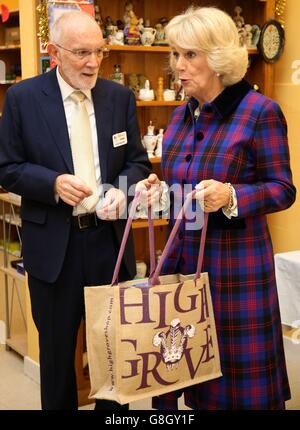 Treuhänder Frank McMahon mit der Herzogin von Cornwall als sie ein Geschenk an die Freiwilligen der Wohltätigkeitsorganisation von High Grove bei einem Besuch der Obdachlosenhilfe Emmaus Village Carlton in Bedfordshire überreicht. Stockfoto