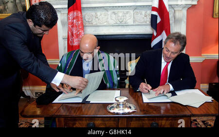 Der britische Premierminister Tony Blair und der Präsident der Islamischen Republik Afghanistan, Hamid Karzai (Mitte), unterzeichnen ein Kooperationsabkommen über 10 Jahre. Stockfoto