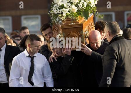 Christy Meli (links) läuft neben dem Sarg seines Sohnes Christopher Meli, der während seiner Beerdigung in der Church of the Annunciation in New Barmsley Green, Belfast, getragen wird. Stockfoto