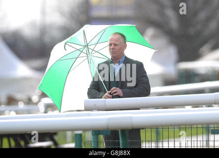 Pferderennen - Lincoln Family Fun Day - Doncaster Racecourse. Ein Rennfahrer untersteht einem Regenschirm auf den Tribünen Stockfoto