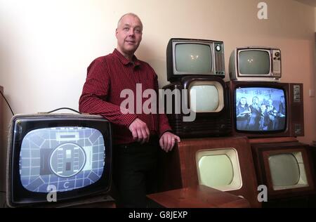 John Thompson steht in seinem Haus in Enfieldm, Nord-London, unter einem Teil seiner Sammlung von Vintage-Schwarz-Weiß-Fernsehern. Tausende Briten haben die Augen vor den Trends für große HD-Fernseher und Streaming-Programme auf Tablets zugunsten ihrer alten schwarz-weiß-Set gedreht. Stockfoto