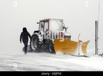 Ein Traktor mit Schneepflug parkte vor dem Tan Hill Inn in Swaledale, North Yorkshire, während Schnee in den Pennines fällt. Stockfoto