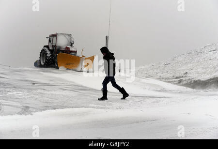 Ein Traktor mit Schneepflug parkte vor dem Tan Hill Inn in Swaledale, North Yorkshire, während Schnee in den Pennines fällt. Stockfoto