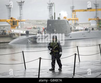 Ein Mitglied der bewaffneten Dienste geht auf dem Deck des Vanguard-Klasse-U-Bootes HMS Vigilant, eines der vier nuklearen Sprengköpfe tragenden U-Boote des Vereinigten Königreichs, mit scharfem U-Boot HMS artful hinter sich, am HM Naval Base Clyde, auch bekannt als Faslane, vor einem Besuch von Verteidigungsminister Michael Fallon. Stockfoto