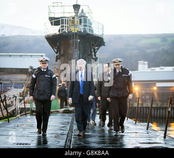 Verteidigungsminister Michael Fallon (Mitte) mit Daniel Martyn (links) Kommandant der HMS Vigilant und Konteradmiral der U-Boote und Assistant Chief of Naval Staff John Weale (rechts) bei einem Besuch des Vanguard-Klasse-U-Bootes HMS Vigilant, eines der vier nuklearen Kriegsheadträger-U-Boote des Vereinigten Königreichs, auf dem HM Naval Base Clyde, Auch bekannt als Faslane, in Schottland. Stockfoto