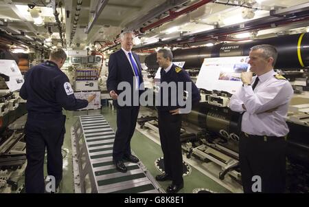 Verteidigungsminister Michael Fallon (Mitte) mit dem Konteradmiral der U-Boote und dem stellvertretenden Leiter des Marinestabs John Weale (zweite rechts) und Daniel Martyn (rechts), dem Kommandanten von HMS Vigilant im Waffenlager während eines Besuchs des U-Bootes HMS Vigilant der Vanguard-Klasse, eines der vier nuklearen U-Boote, Am HM Naval Base Clyde, auch bekannt als Faslane, in Schottland. Stockfoto