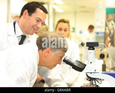 Schatzkanzler George Osborne (2. Links) sieht, wie der Mitbegründer von Microsoft Bill Gates bei einem Besuch der Liverpool School of Tropical Medicine in Liverpool durch ein Mikroskop schaut, während sie sich zusammenschließen, um Malaria zu bekämpfen. Stockfoto