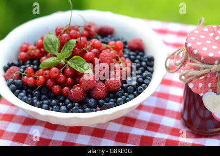 Frische Beeren und Himbeermarmelade, serviert im Sommergarten Stockfoto